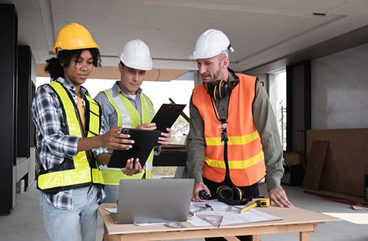 Engineering Team Collaborates on Work Plan in Modern Construction Site with Safety Gear and Equipment